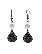 Load image into Gallery viewer, The Moonpetal Lace Teardrop Earrings feature a wide, full teardrop frame in antique bronze brass, filled with an intricate botanical scrollwork pattern. Behind the lace, a white polymer clay backing glows softly, making every curl and flourish of the filigree stand out in beautiful contrast.
The shape is generous and presence-filled without being heavy. The white grounds the ornate bronze, keeping the whole piece feeling fresh, clean, and quiet sophisticated.